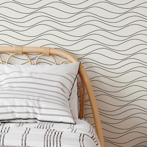 Peut inclure: Scène de chambre avec un lit orné d'un oreiller et d'une literie à rayures. La tête de lit est en bois clair. Le mur derrière le lit présente un fond crème avec un motif ondulé noir.