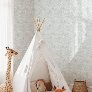 May include: A white teepee tent with wooden poles and pom-pom accents, set in a child's room. A stuffed giraffe, deer pillow, and other toys are nearby. The wallpaper has a wavy blue pattern.