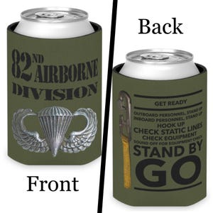 Puede incluir: Enfriador de latas verde oliva con el texto "82nd Airborne Division" y un emblema de paracaídas. La parte trasera presenta instrucciones y las palabras "Stand By Go".