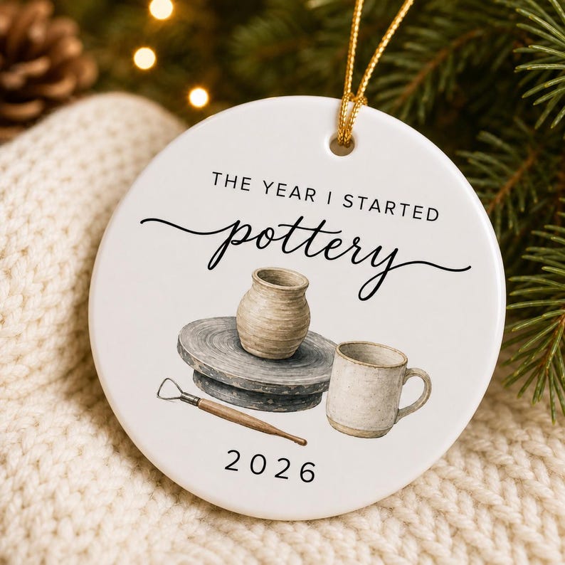 Close-up of the glossy white ceramic pottery ornament showing watercolor clay tools, wheel-thrown vase and personalized year.