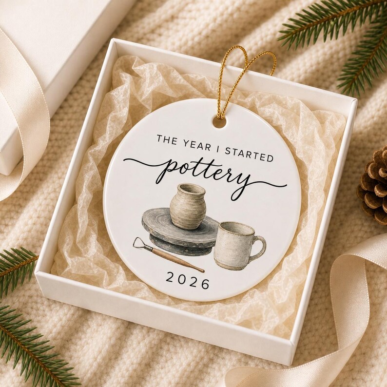 Round pottery ceramic ornament presented inside a white gift box with tissue paper and fine gold hanging string.