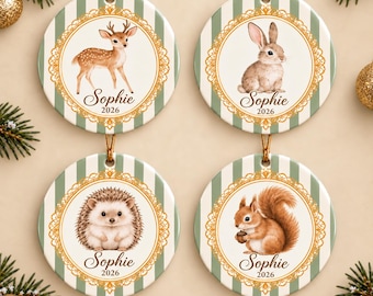 May include: Four round ceramic ornaments featuring green and white vertical stripes. Each ornament displays a gold filigree border, the name Sophie, the year 2026, and a woodland animal: a deer, a rabbit, a hedgehog, and a squirrel.
