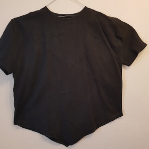 May include: A black short-sleeved t-shirt with a unique design featuring stitched lines across the front.