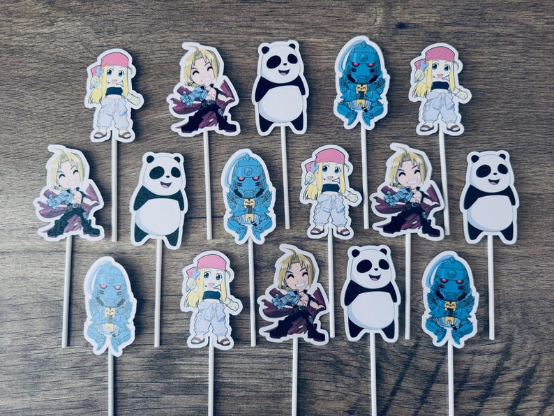 Puede incluir: Un conjunto de quince adornos para cupcakes con ilustraciones de personajes rubios, figuras con armadura azul y pandas en blanco y negro. Cada recorte est&aacute; unido a un palillo blanco fino, mostrando varios dise&ntilde;os de estilo anime.