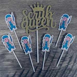 Puede incluir: Un adorno para pastel con purpurina dorada que muestra el texto Scrub Queen con una corona encima, acompa&ntilde;ado de cinco adornos individuales para cupcakes, cada uno con una enfermera rubia con uniforme azul y un instrumento.