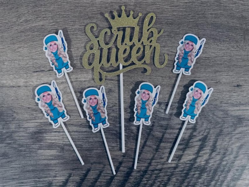 Puede incluir: Un adorno para pastel con purpurina dorada que muestra el texto Scrub Queen con una corona encima, acompa&ntilde;ado de cinco adornos individuales para cupcakes, cada uno con una enfermera rubia con uniforme azul y un instrumento.