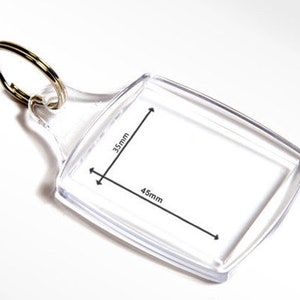 May include: Clear plastic keyring with a rectangular photo insert measuring 4.5cm by 4.5cm. The keyring has a metal ring for attaching to keys.