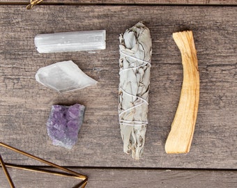 May include: A collection of crystals and smudging tools, including a white sage bundle, palo santo stick, selenite wand, and amethyst cluster. These items are commonly used in spiritual practices and rituals.