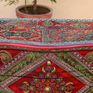May include: A red wooden chest with three drawers, each decorated with intricate hand-painted floral and paisley designs in vibrant colors like green, gold, and blue.