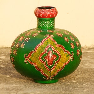 May include: A green ceramic vase with intricate floral and geometric patterns painted in red, yellow, and white. The vase has a round body and a narrow neck with a red rim.