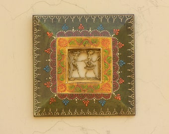 Könnte beinhalten: Ein quadratischer Holzrahmen mit grünem Hintergrund und aufwendigen goldenen und bunten floralen Designs. Im Inneren des Rahmens befindet sich ein kleinerer quadratischer Rahmen mit weißem Hintergrund und einer goldenen Ausschnitt von zwei tanzenden Figuren.
