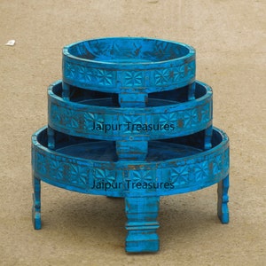 May include: A three-tiered round table made of wood, painted in a bright blue color. The table has intricate carvings and the words "Jaipur Treasures" are printed on the bottom tier.