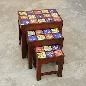 May include: Three wooden nesting tables with colorful tile tops. The tiles feature floral patterns in shades of blue, yellow, red, and green.