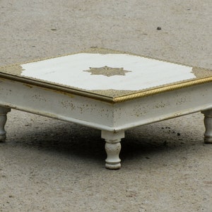 May include: White wooden coffee table with a gold trim and a decorative gold star design in the center of the top.