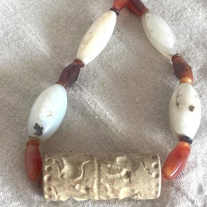 Colgante con sello cilíndrico de deidad del antiguo Cercano Oriente, granates, ágatas, plata de ley