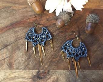 May include: A pair of grey macrame earrings with gold accents and pointed metal dangles.