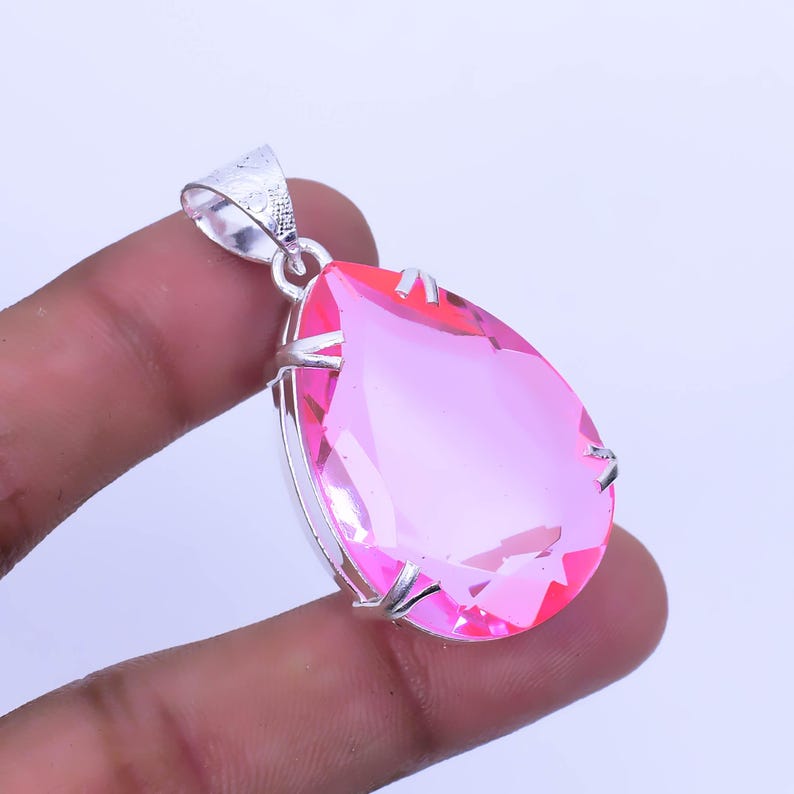 May include: A pink teardrop-shaped gemstone pendant set in a silver setting.