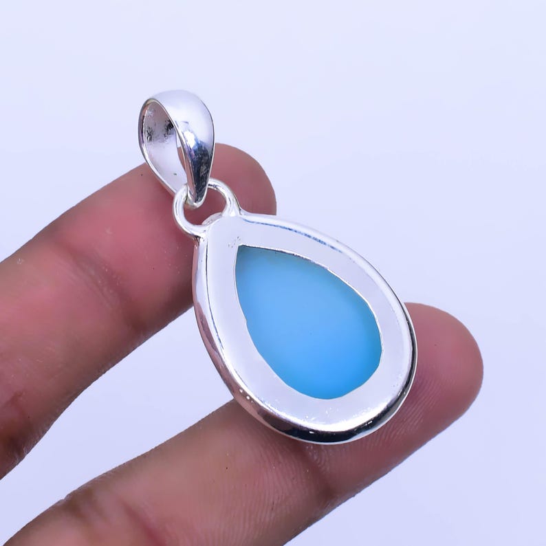 May include: A teardrop-shaped pendant with a light blue gemstone set in a silver frame.