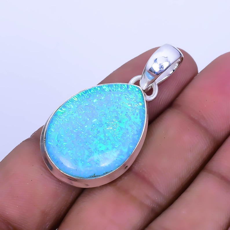 May include: A teardrop-shaped pendant with a blue opal gemstone set in sterling silver. The opal has a shimmering, iridescent finish.