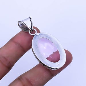 Peut inclure: Pendentif en argent avec une pierre ovale rose p&acirc;le sertie dans un cadre en argent aux d&eacute;tails complexes.