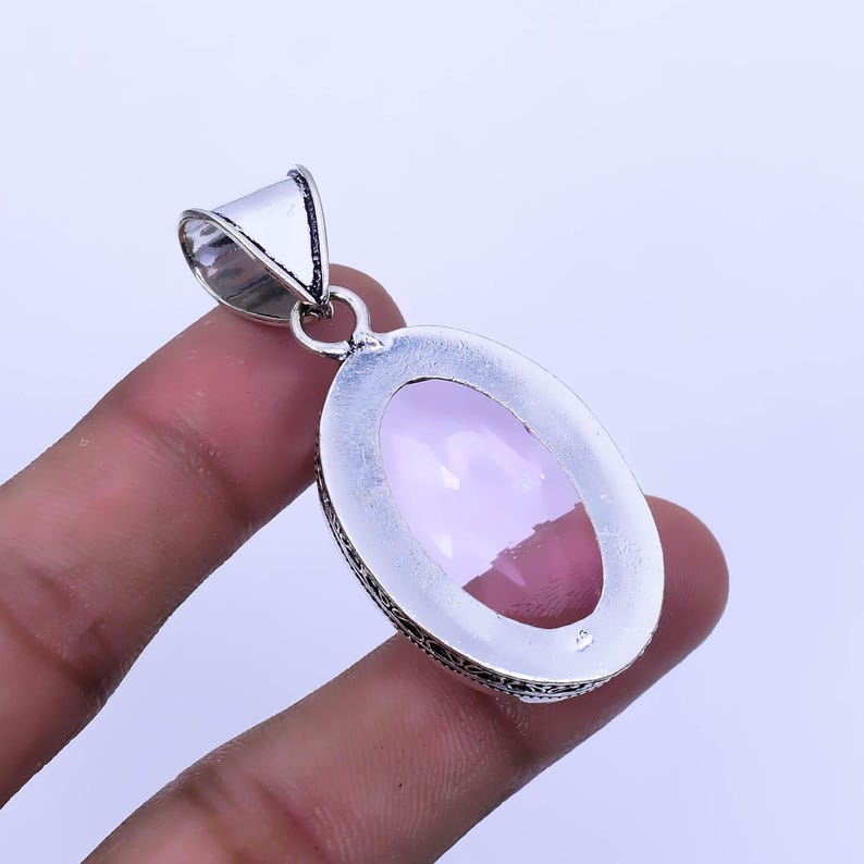 Peut inclure: Pendentif en argent avec une pierre ovale rose p&acirc;le sertie dans un cadre en argent aux d&eacute;tails complexes.
