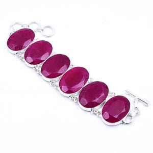 Puede incluir: Un brazalete de plata con seis piedras preciosas ovaladas de color rojo intenso. Las piedras están engastadas en biseles individuales de plata y conectadas por una delicada cadena. Cierre de palanca.