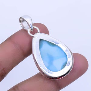 May include: A teardrop-shaped pendant with a blue and white gemstone set in a silver frame. The pendant is hanging from a silver bail.
