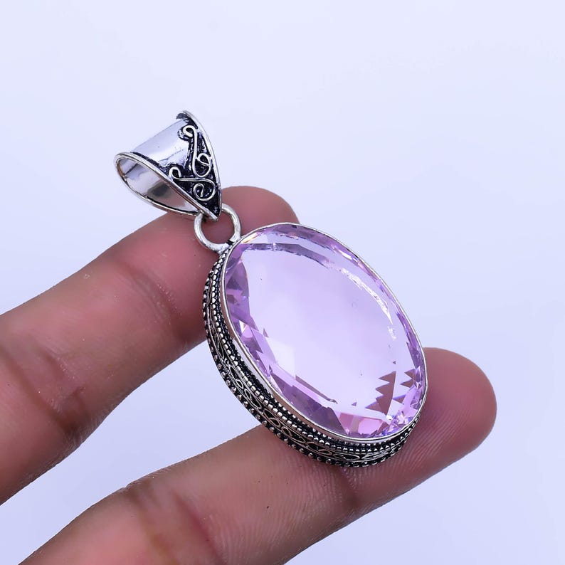 Peut inclure: Un pendentif en argent avec une pierre pr&eacute;cieuse rose ovale sertie dans un motif de filigrane.