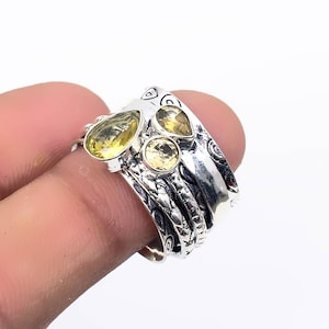 May include: A silver ring with a textured band and four yellow gemstones. The ring is designed to be worn as a stackable ring.