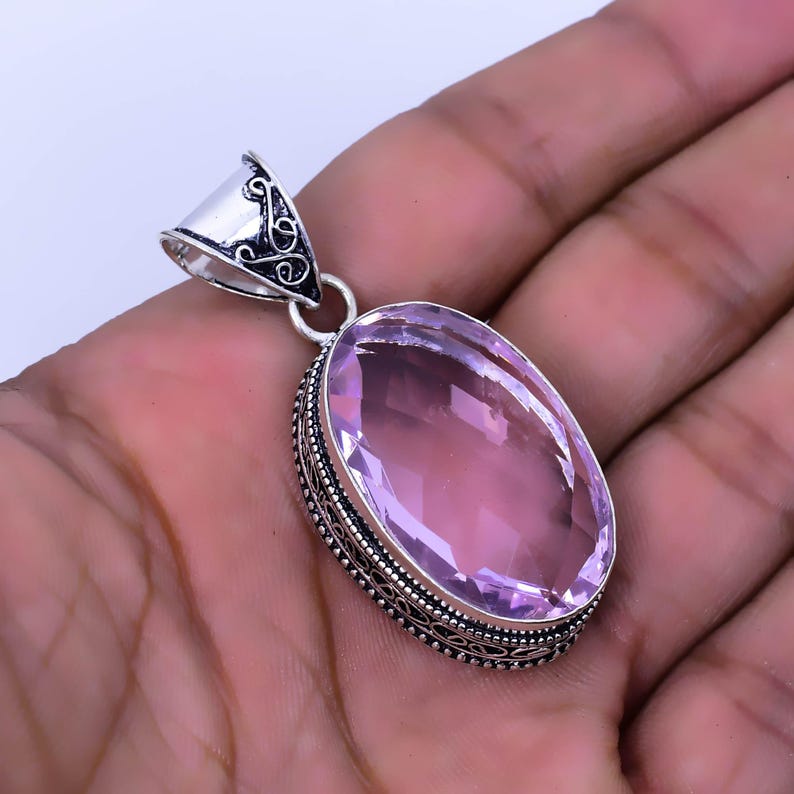 Peut inclure: Un pendentif en argent avec une pierre pr&eacute;cieuse ovale rose p&acirc;le sertie dans un motif de filigrane.