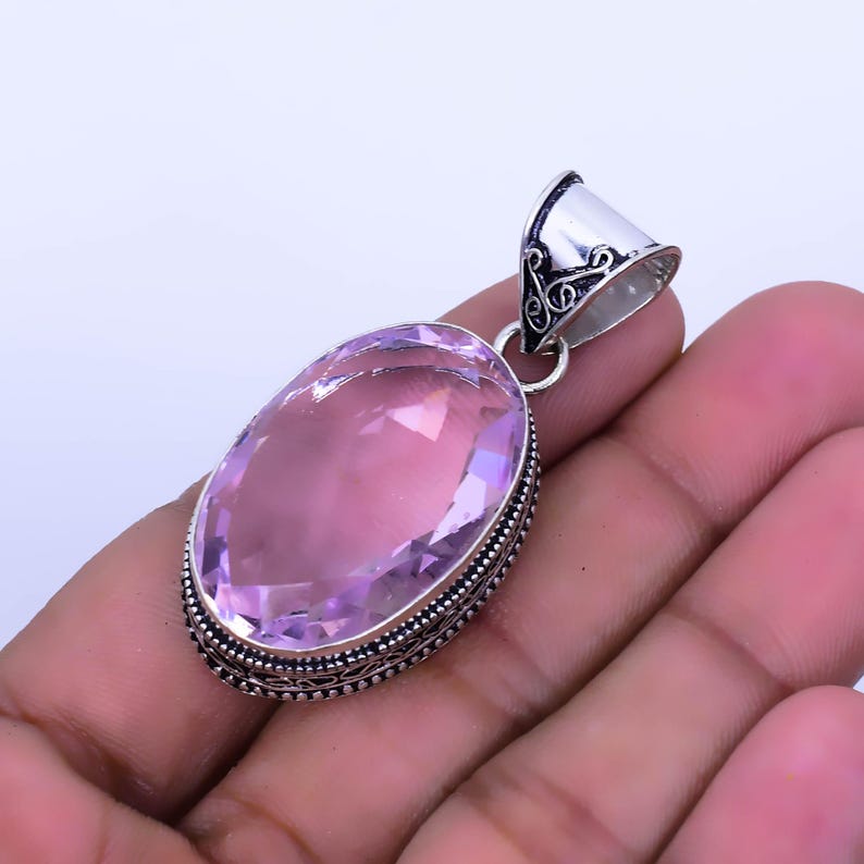 Peut inclure: Un pendentif en argent avec une pierre pr&eacute;cieuse rose de forme ovale sertie dans une b&eacute;li&egrave;re en argent. Le pendentif a une b&eacute;li&egrave;re en argent orn&eacute;e.
