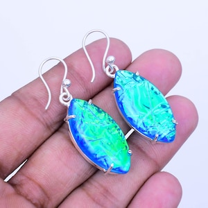 May include: A pair of silver earrings with a leaf-shaped design. The earrings feature a vibrant combination of blue and green colors. The earrings are held in place by silver hooks.