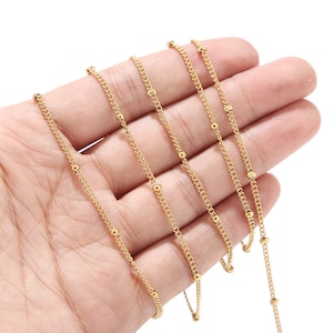 Peut inclure: Un collier doré délicat avec une chaîne gourmette ornée de petites perles espacées régulièrement. Le collier est présenté sur un fond neutre, mettant en valeur ses détails fins et sa finition polie. Idéal pour être porté seul ou superposé.