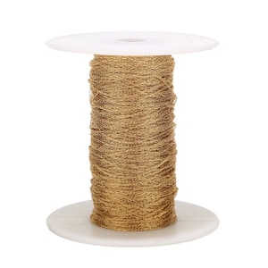 May include: A spool of gold-coloured chain on a white plastic spool. The chain is wound tightly around the spool.