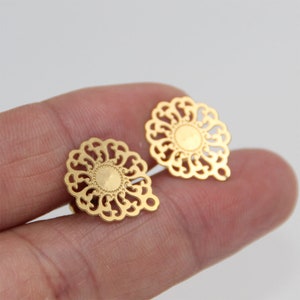 May include: Two gold-colored metal filigree embellishments with a circular design. The embellishments have a delicate, intricate pattern and a smooth, shiny finish.