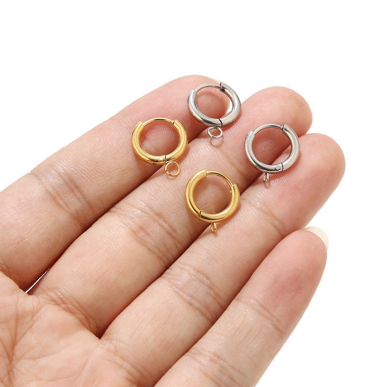 May include: Three earring hoops with a jump ring closure. Two are gold and one is silver.
