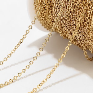 Könnte beinhalten: Nahaufnahme einer goldenen Kette mit einem strukturierten, runden Gliederdesign. Die Kette ist aufgerollt und scheint aus Metall zu sein.