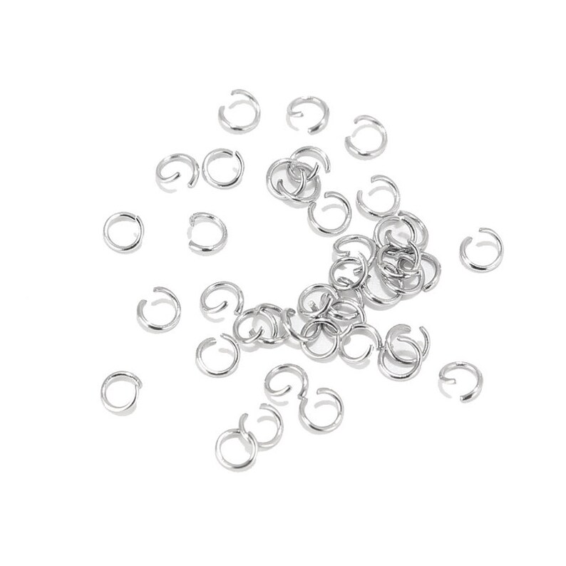 May include: A scattering of silver jump rings, a type of jewellery finding used for connecting chains, cords, and other jewellery components.