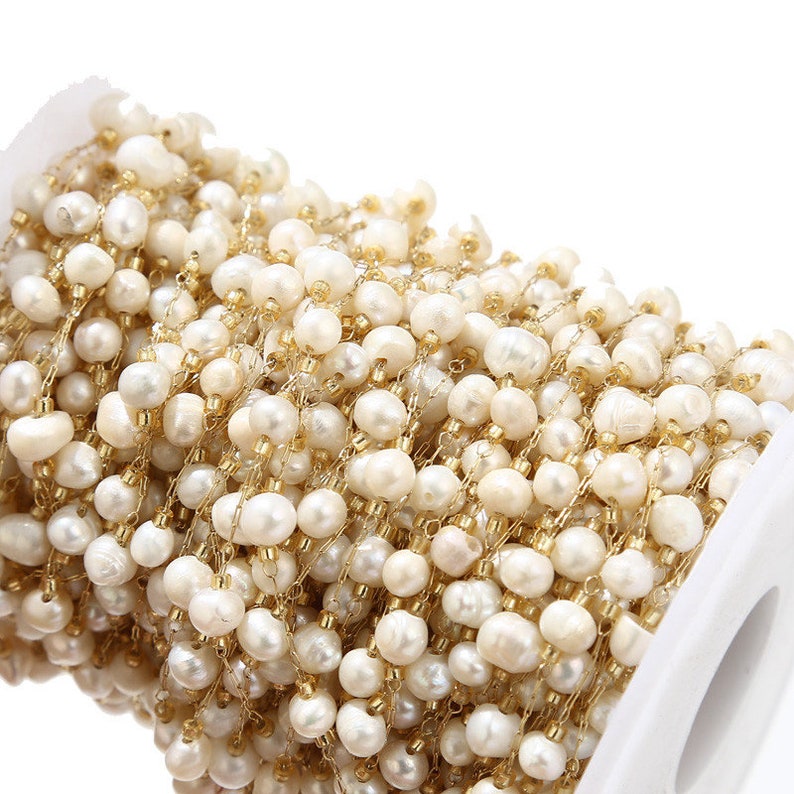 Puede incluir: Un carrete de cadena de perlas blancas y doradas, ideal para la elaboraci&oacute;n de joyas. La cadena est&aacute; hecha de peque&ntilde;as perlas redondas y eslabones de metal dorado.