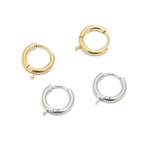 May include: Four hoop earrings, two gold and two silver, with a hinged clasp. The earrings are all the same size and shape.