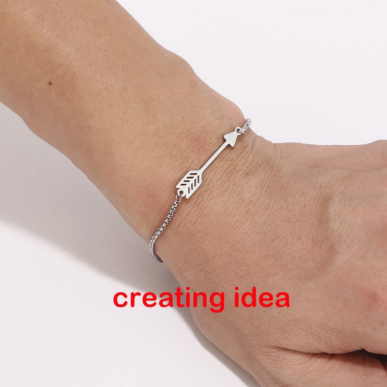 May include: A silver chain bracelet with an arrow charm. The arrow is pointing to the right.