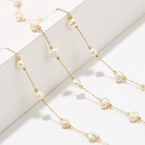 Puede incluir: Un delicado collar de cadena dorada con perlas blancas. La cadena est&aacute; hecha de peque&ntilde;os c&iacute;rculos unidos y las perlas est&aacute;n espaciadas uniformemente.
