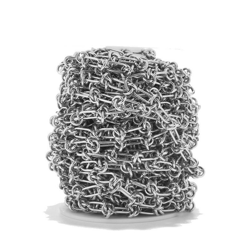 May include: A silver chain link is coiled and wrapped around a white spool. The chain is made of metal and has a shiny finish.