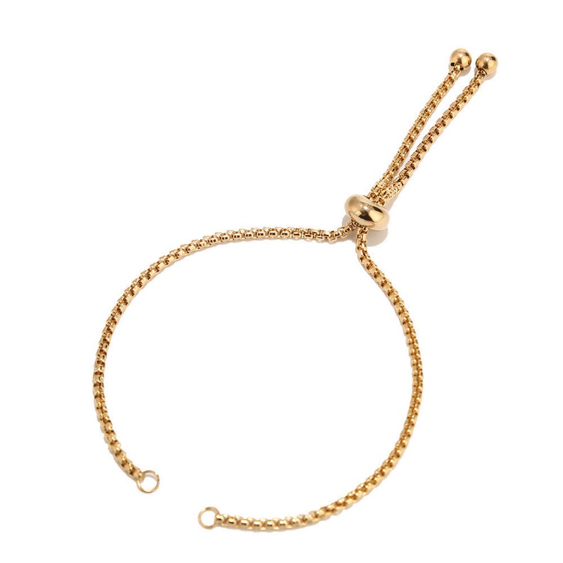 May include: A gold chain bracelet with a sliding clasp. The bracelet is made of a delicate chain and has a simple design.