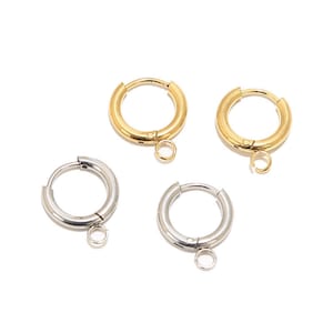 May include: Four hoop earrings with a small dangling circle. Two earrings are gold and two are silver.