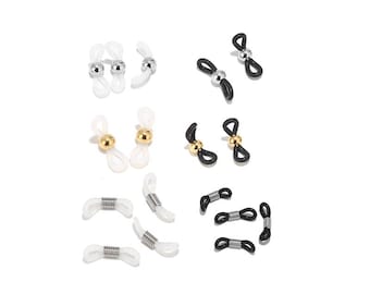 May include: Assortment of white and black eyeglass chain holders with gold and silver accents. The holders are made of plastic and metal and feature a spring-loaded design.