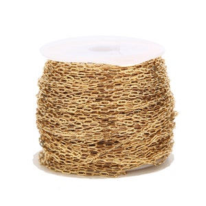 May include: A spool of gold-coloured chain with oval links. The chain is tightly wound around a white plastic spool. The chain is a bright, shiny gold colour, and the links are uniform in size and shape. This chain is suitable for jewellery making.