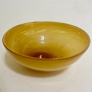 May include: A large, amber-colored glass bowl with a swirling pattern. The bowl is empty and has a smooth, glossy finish.