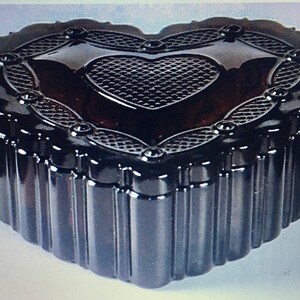 May include: A black heart-shaped glass trinket box with a raised, patterned heart design on the lid. The box has a ribbed texture around the sides.