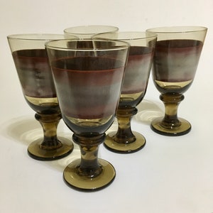 Puede incluir: Juego de cuatro copas de vino de vidrio marrón y transparente con un diseño degradado marrón y blanco.